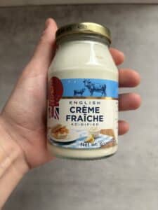 Hand holding jar of English crème fraîche.