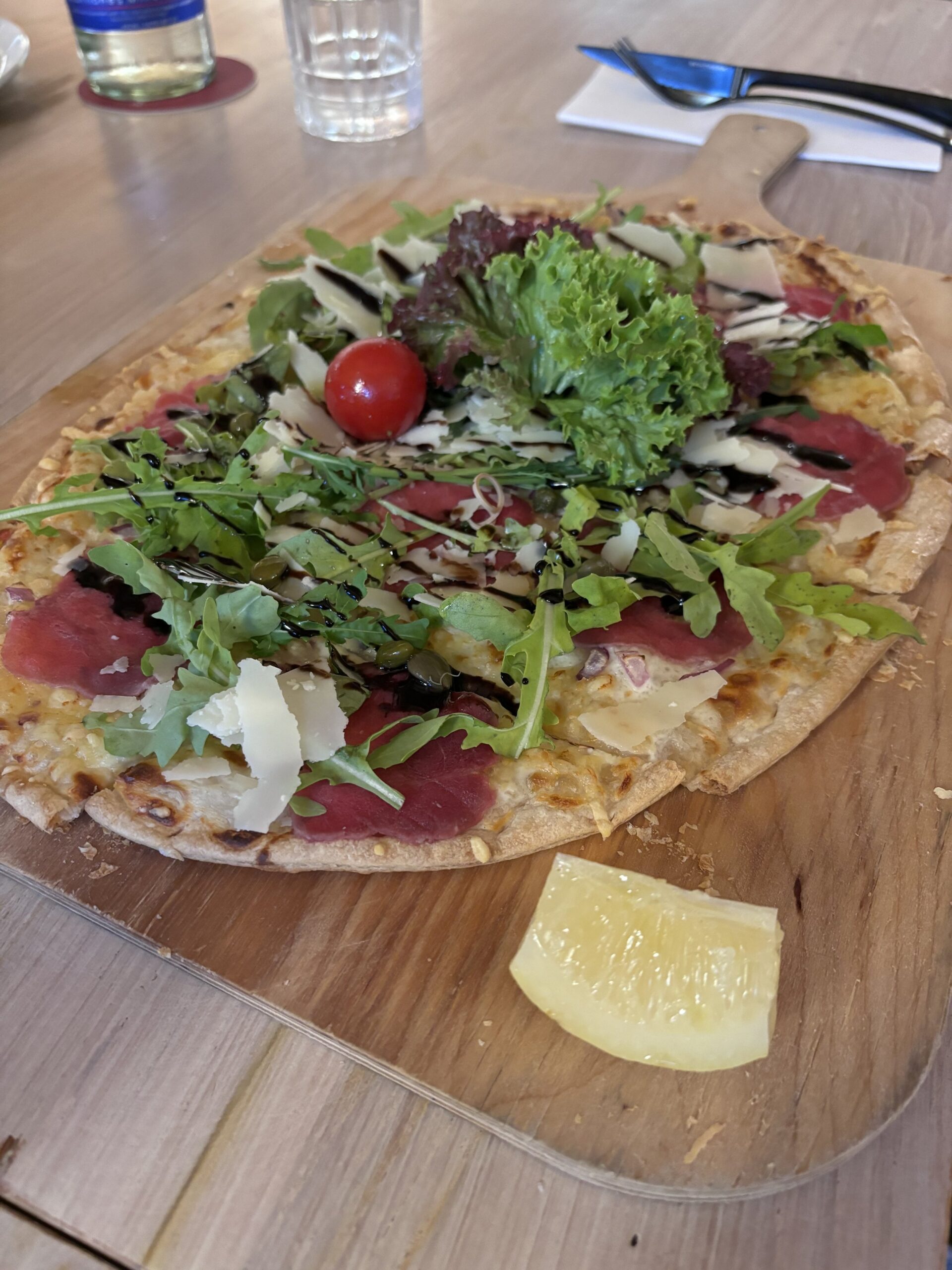 Gourmet pizza with arugula, cherry tomato, and parmesan.