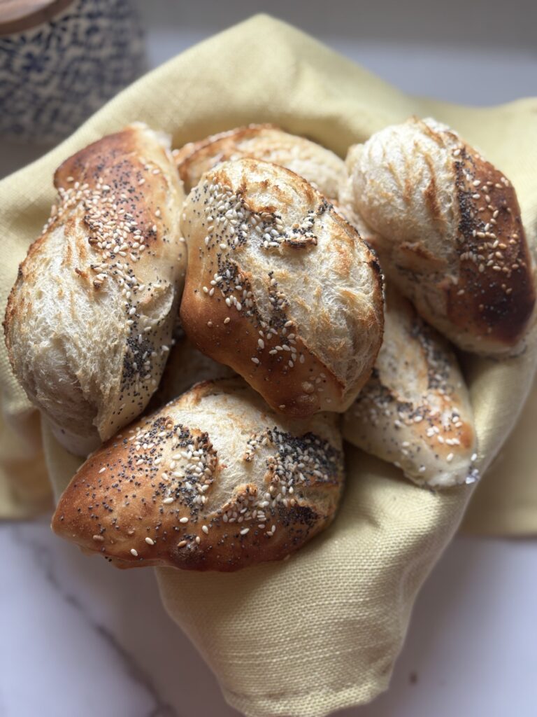Freshly baked seed-coated artisanal bread rolls in basket.