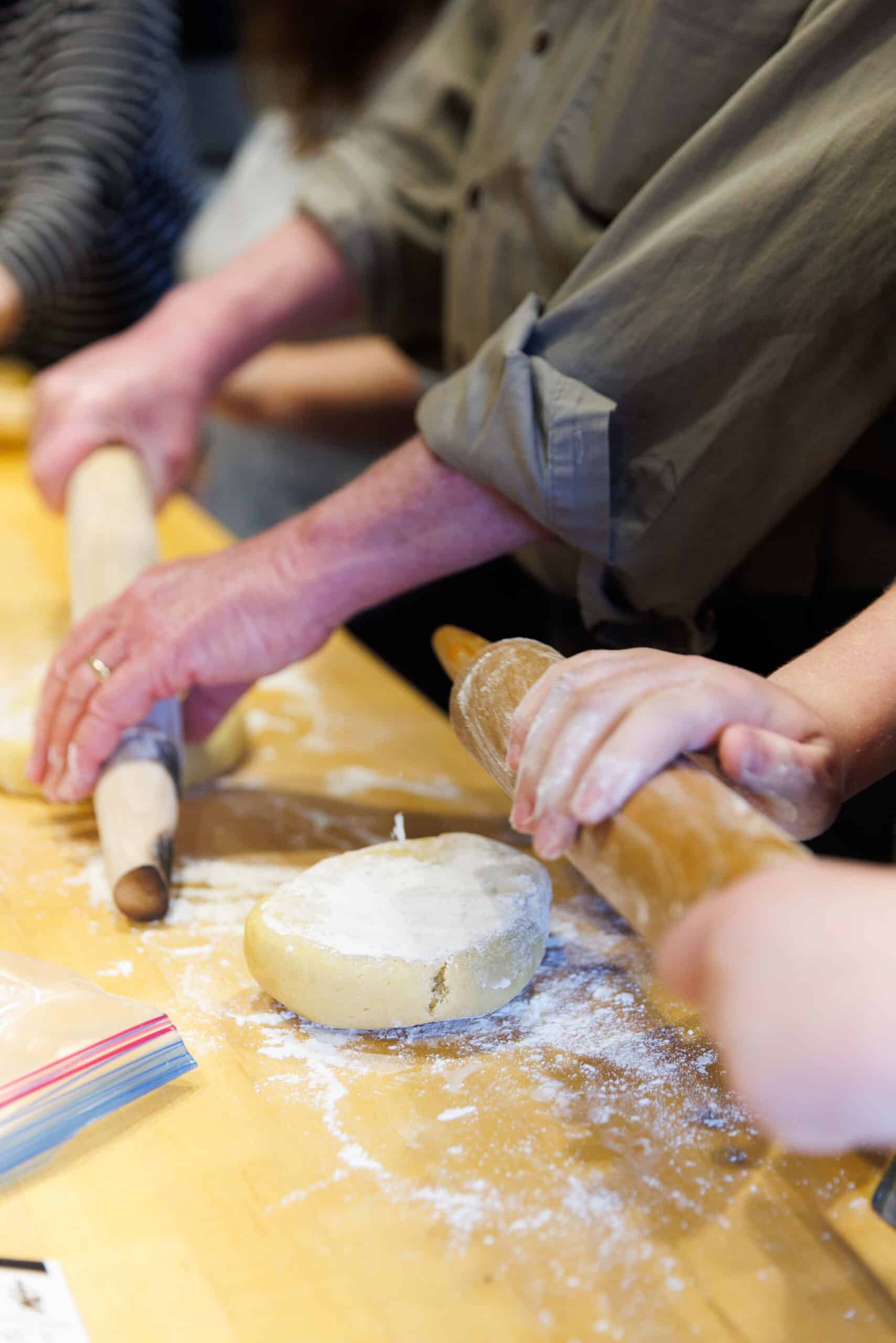 Hands rolling out dough on floured surface