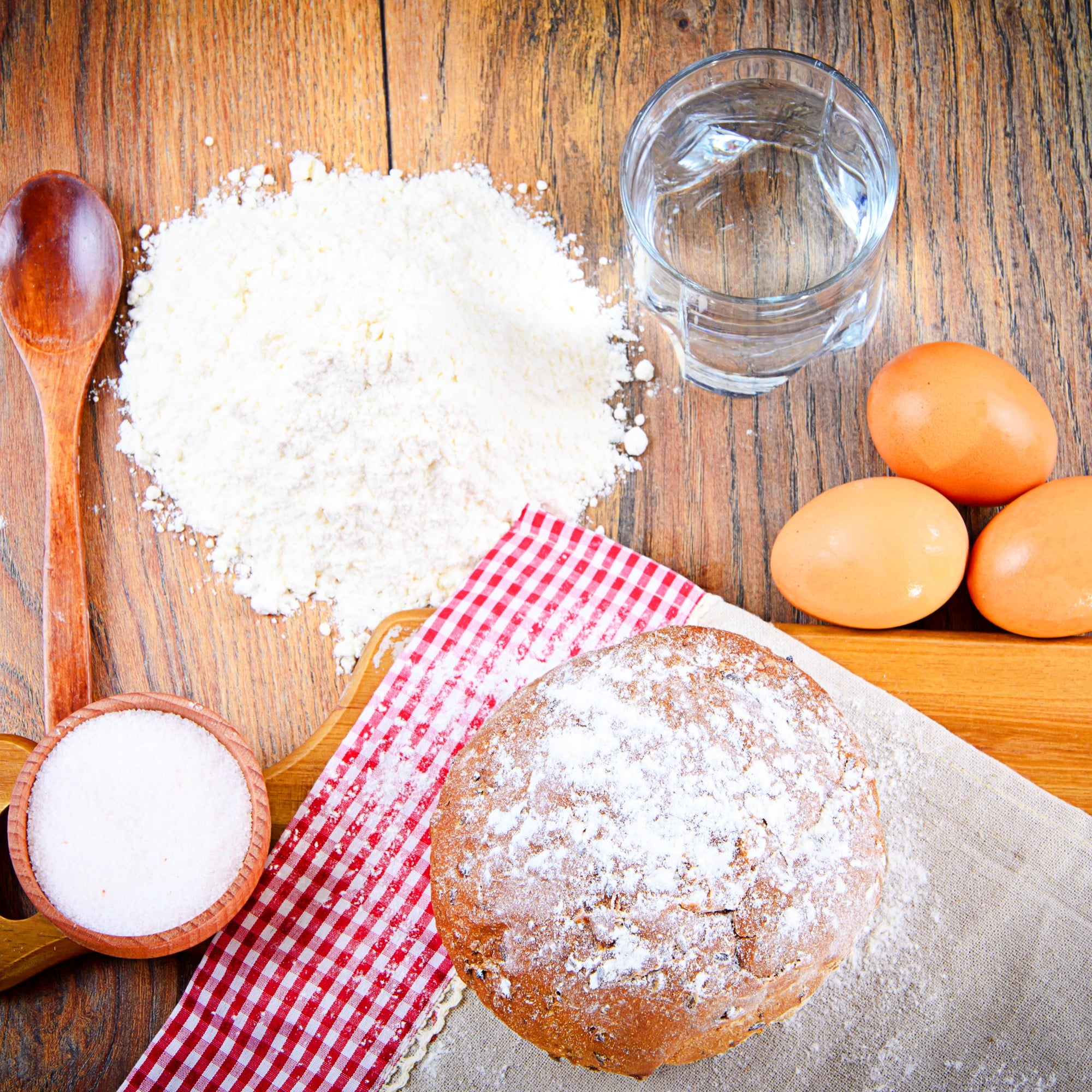 Baking ingredients and bread on wooden surface.