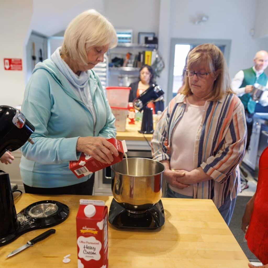 Women in Baking class pouring cream into bowl to make fig tart