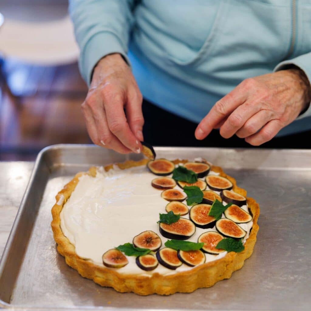 Assembling fig tart by placing fresh figs on the fig dessert