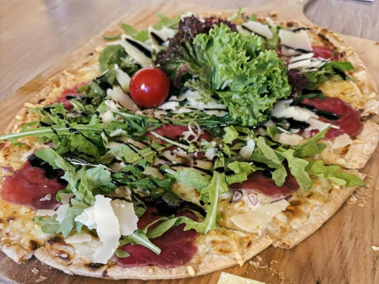 Gourmet pizza topped with greens and Parmesan shavings.