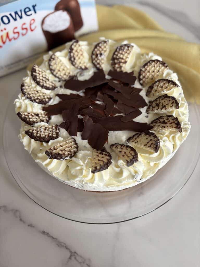 “German Schokokuss cream cake on a table with a box of chocolate foam kisses (Schaumküsse) in the background”