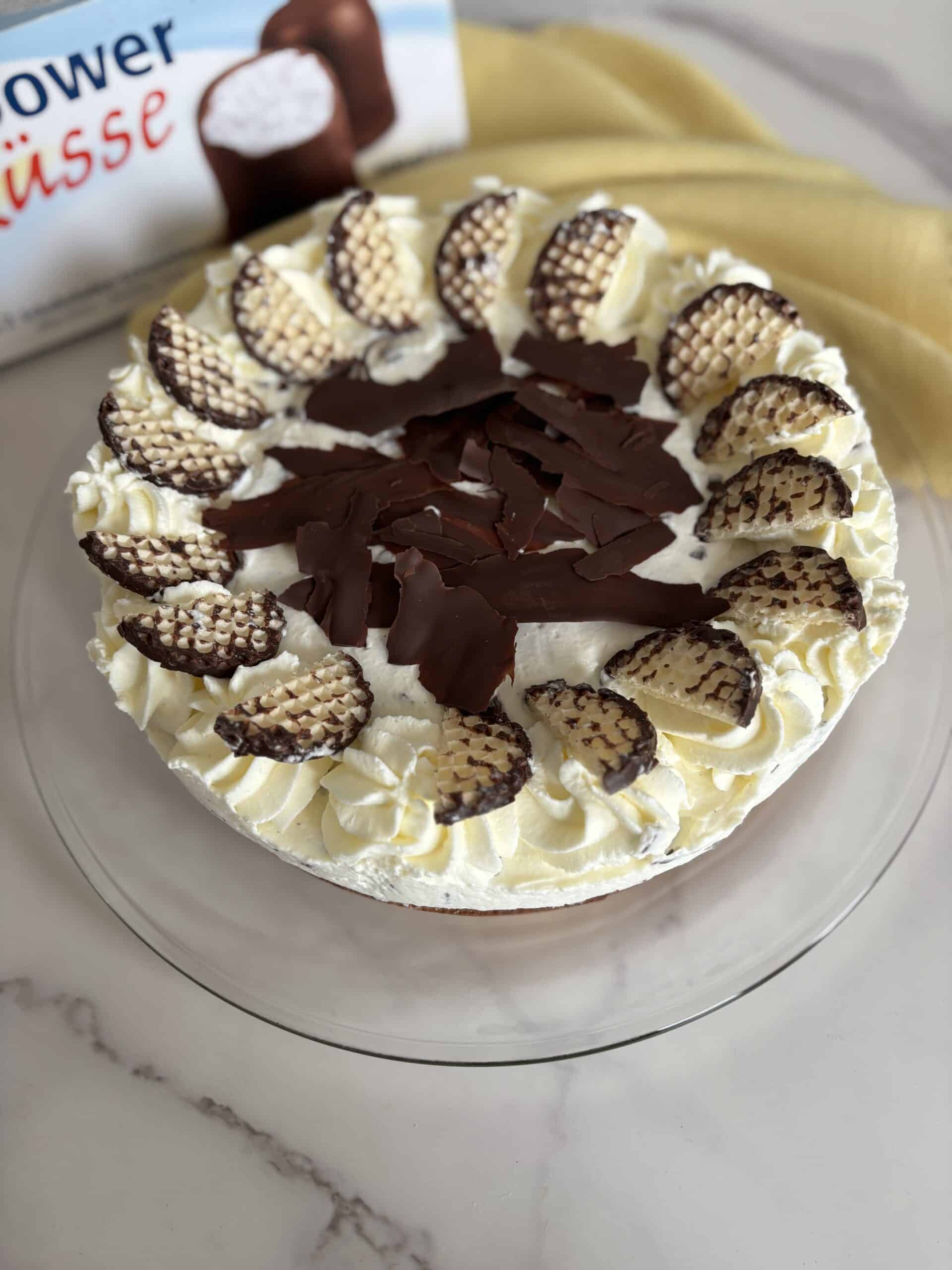 “German Schokokuss cream cake on a table with a box of chocolate foam kisses (Schaumküsse) in the background”