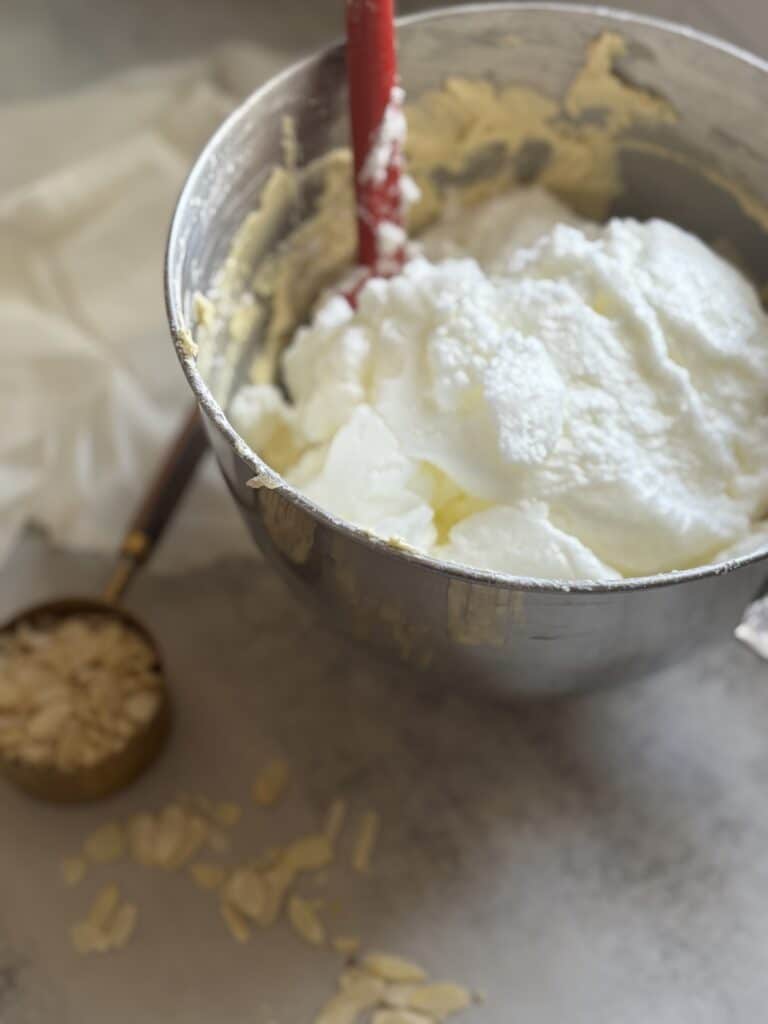 Mixing white cream in metal bowl with spatula