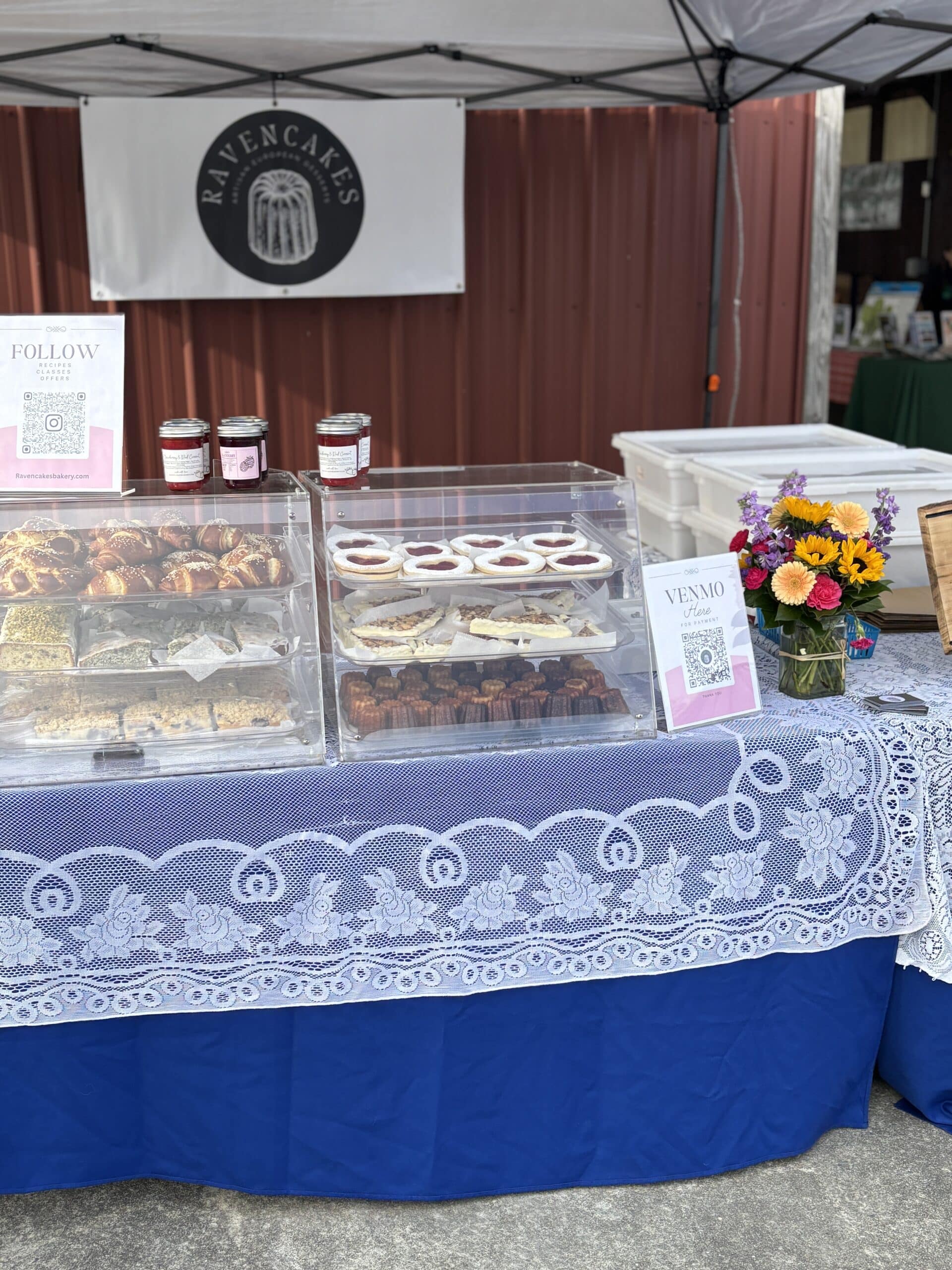 Ravencakes bakery stall with assorted pastries and flowers.
