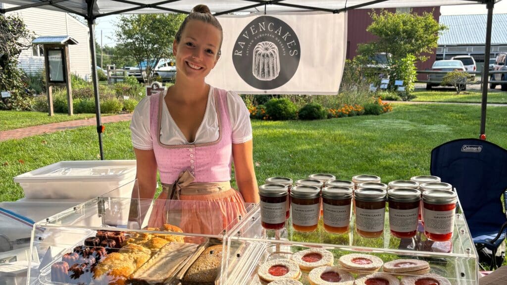 Smiling vendor selling pastries at farmers market.