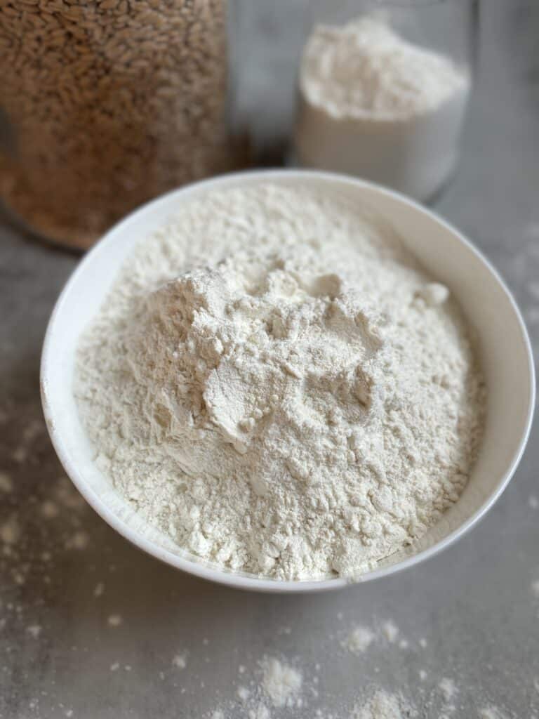 Bowl of white flour on a grey surface.
