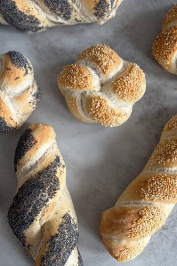 poppyseed rolls and sesame seeds laying on surface.
