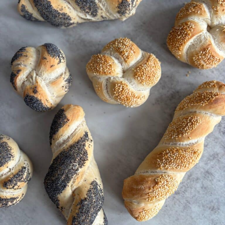 poppyseed rolls and sesame seeds laying on surface.