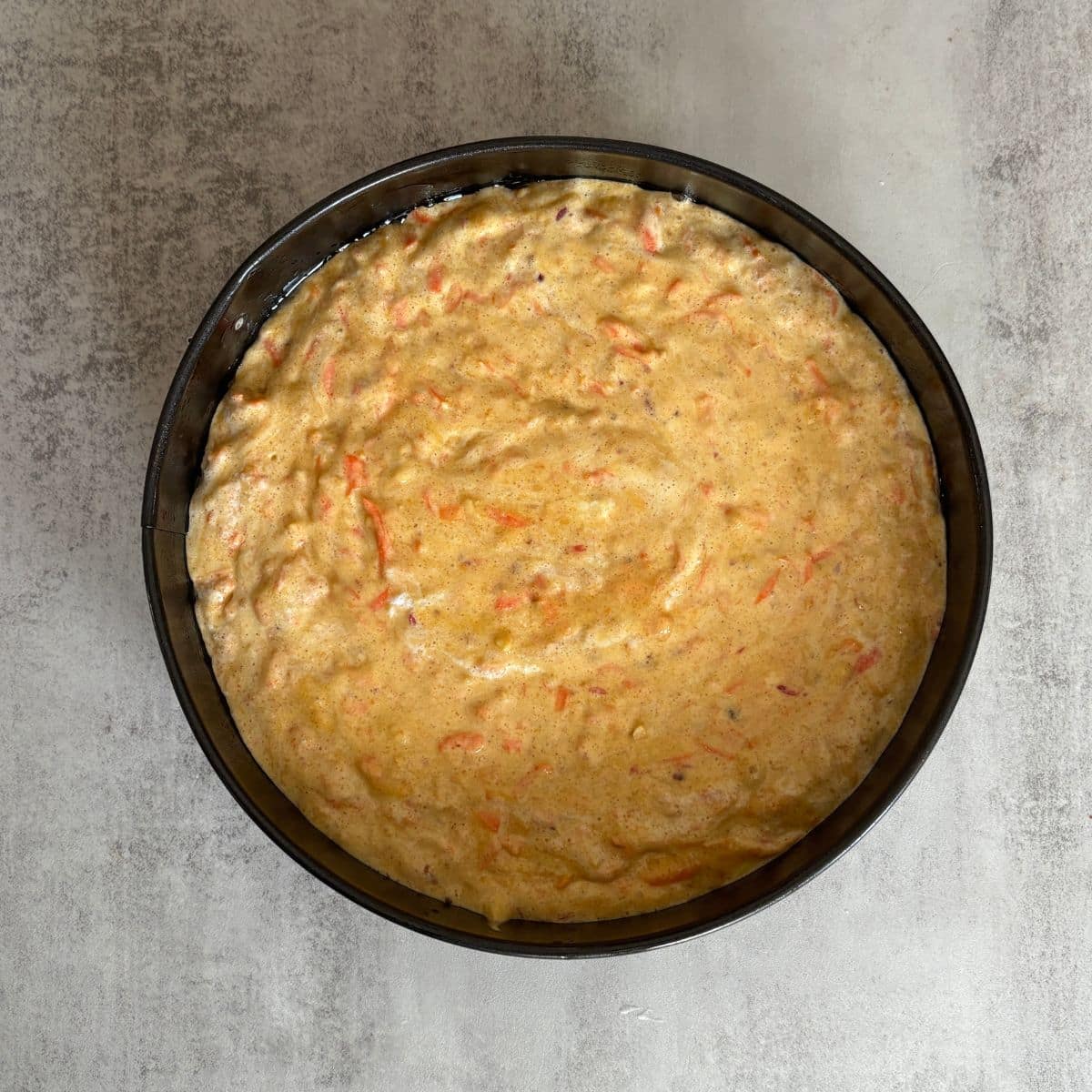 Carrot orange cake batter poured into prepared springform pan, ready to bake