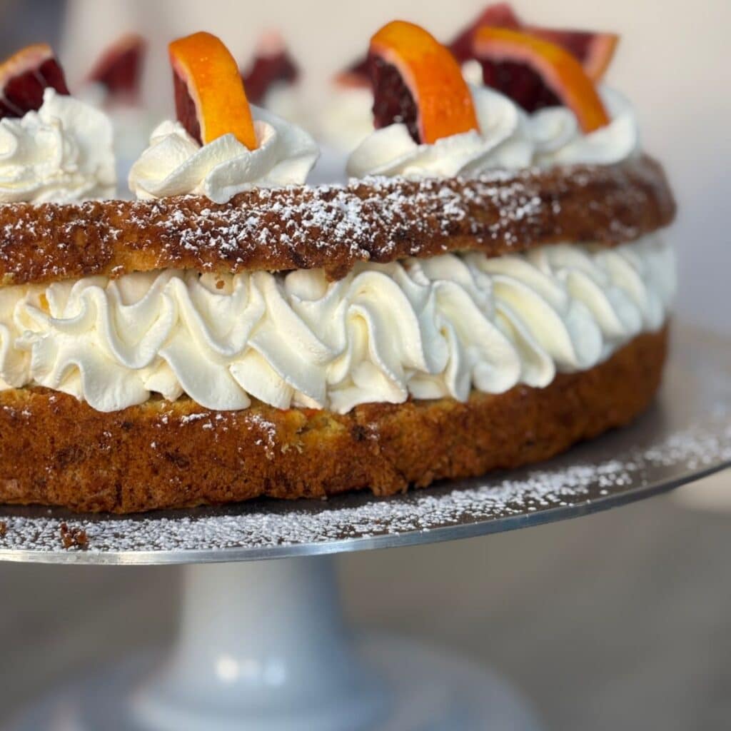 Carrot orange cake sliced in half with whipped blood orange cream filling