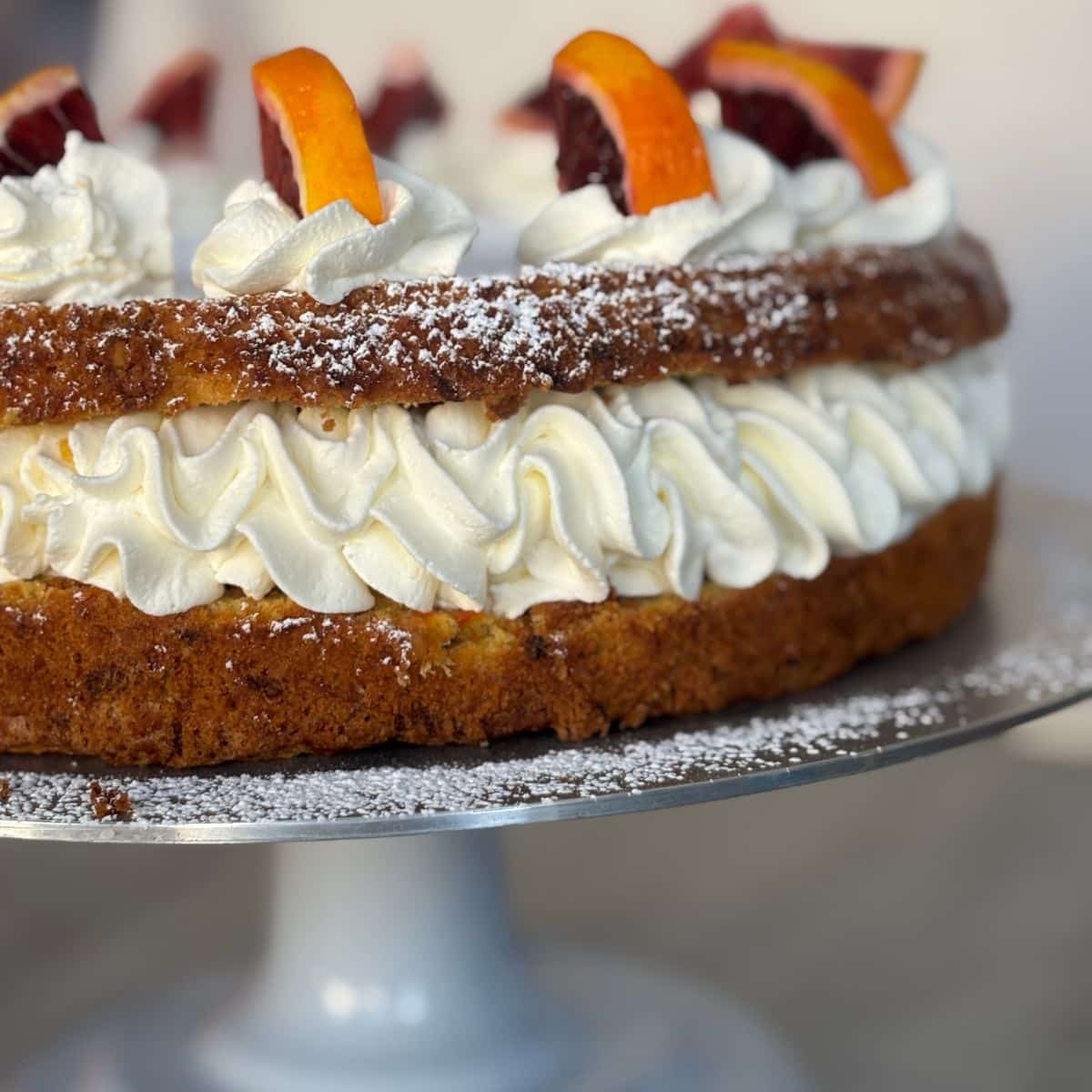 Carrot orange cake sliced in half with whipped blood orange cream filling