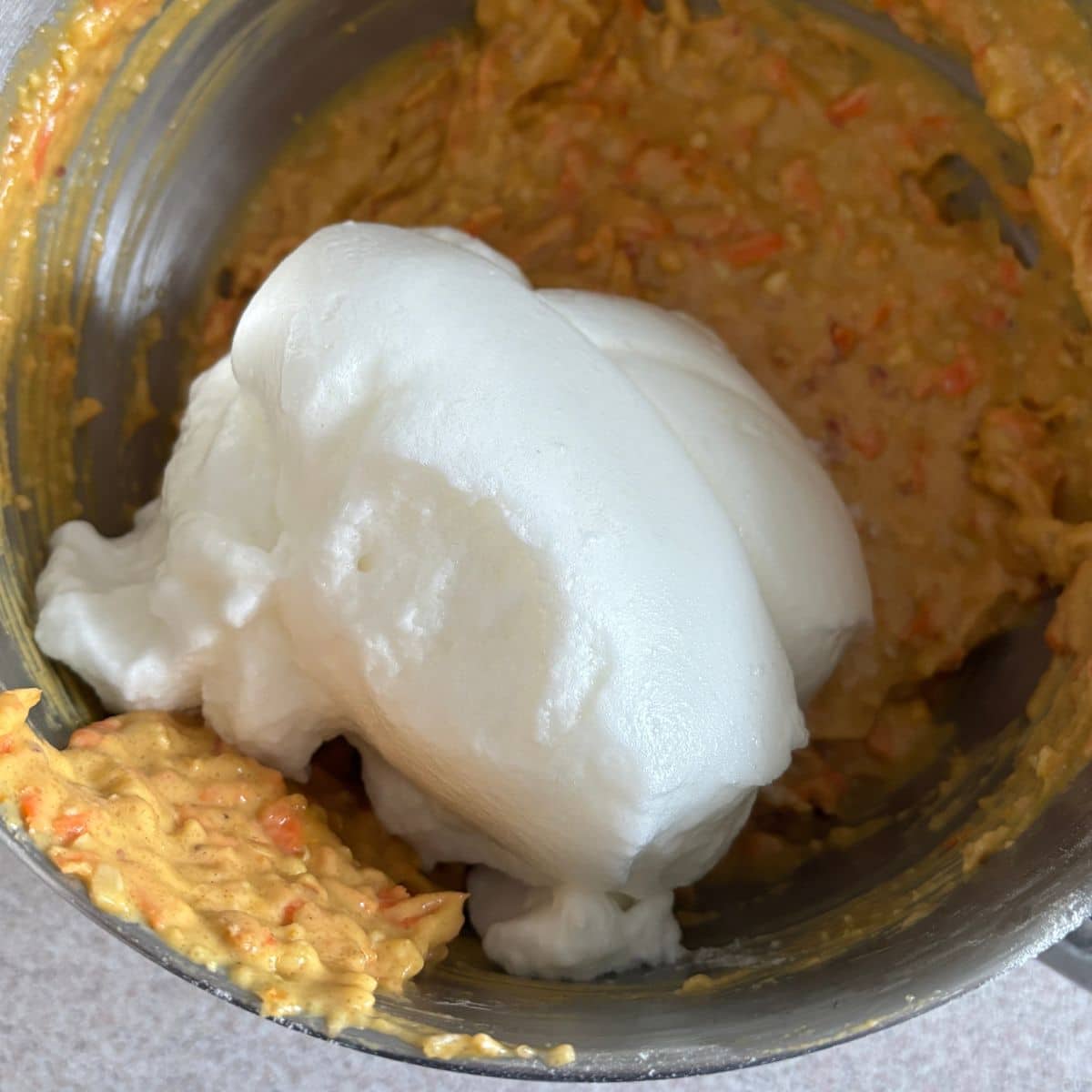 Whipped egg whites being folded into carrot orange cake batter