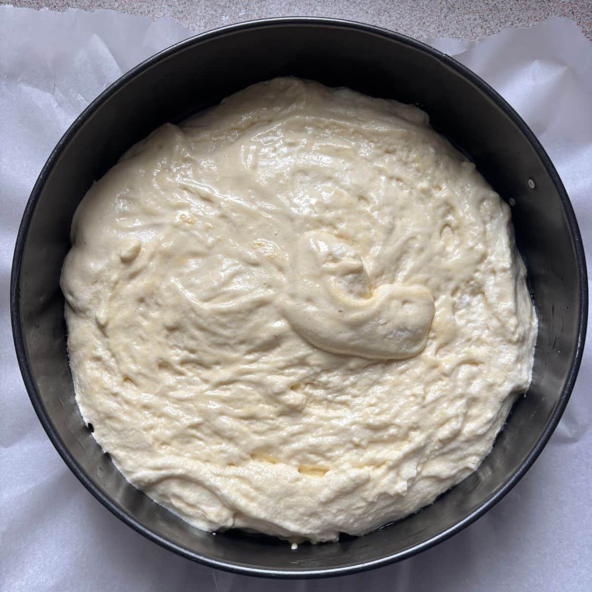 Sponge cake batter in a lined 10 inch pan ready to bake for strawberry mascarpone cake