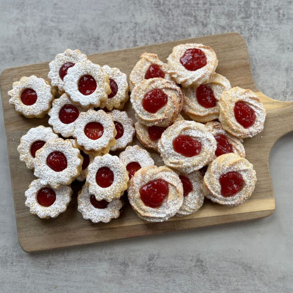 Marzipan Strawberry Cookies and Linzer Cookies on wooden board